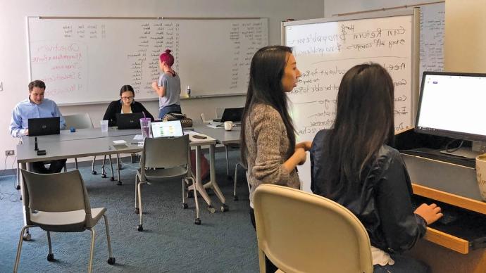 five staff members studiously work at whiteboards and desks