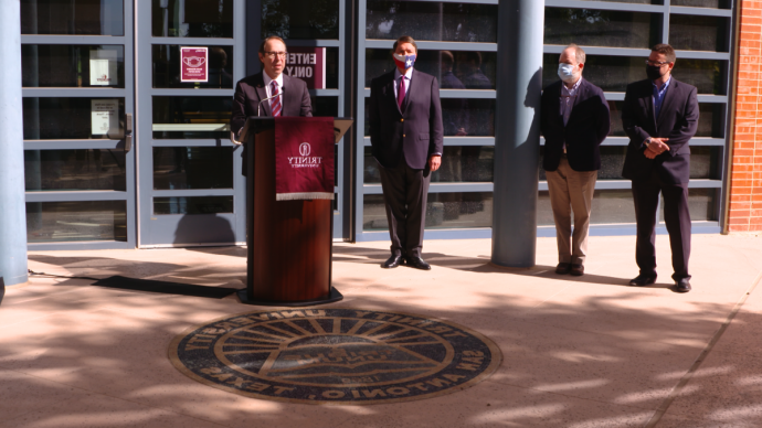 丹尼·安德森 speaking at podium outside of Northrup Hall with three men to the side of him