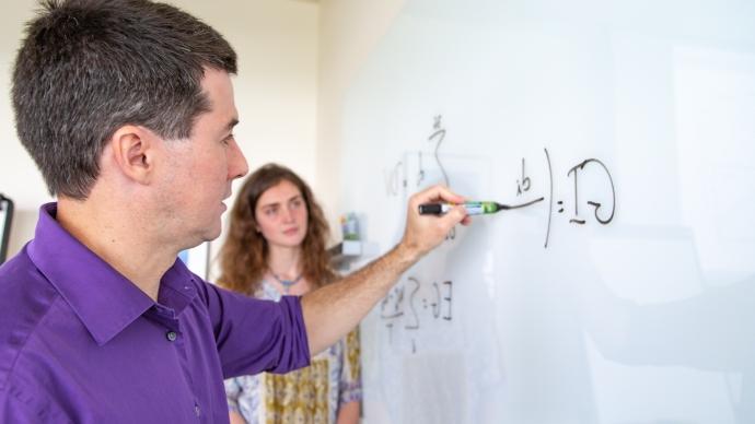 Cabral Balreira writes a mathematical equation on a whiteboard