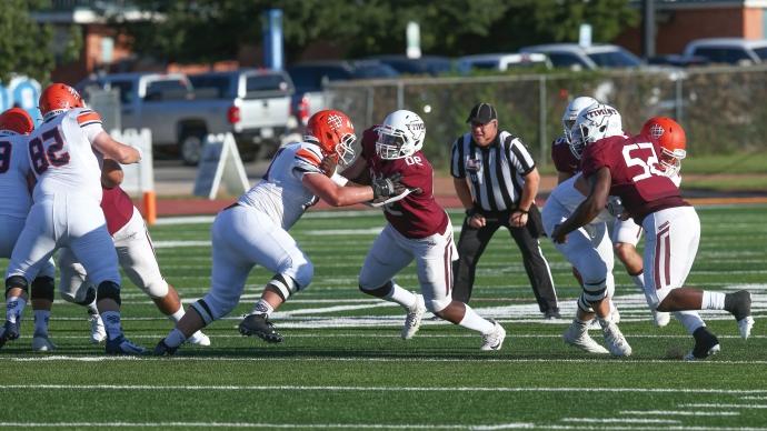 trinity football players in middle of game against macalester college in trinity's football stadium