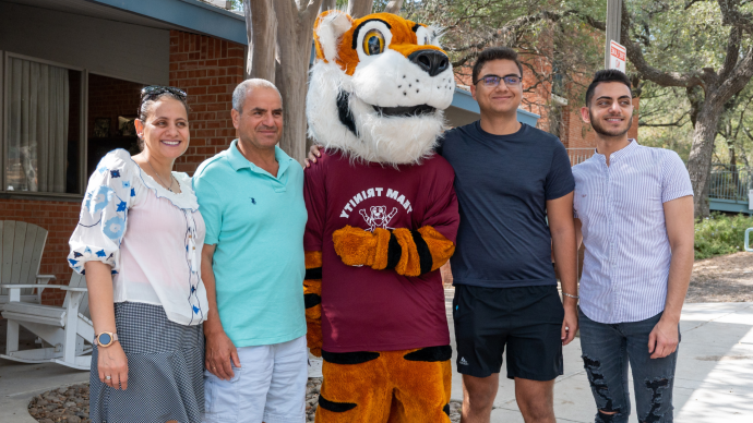 A family of four poses outside the Witt Center with LeeRoy the Tiger