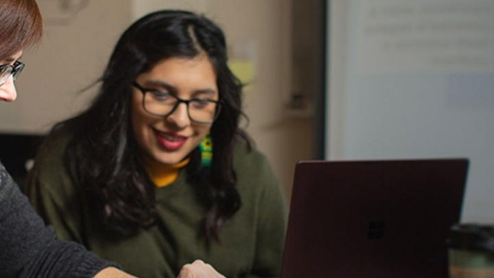 Student works with her professor on a laptop