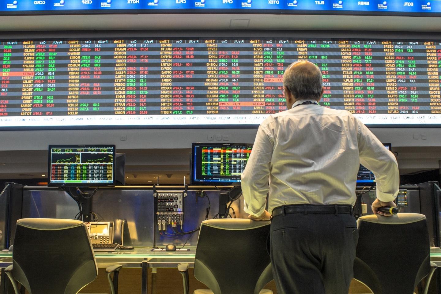 People looking at the stock exchange numbers on giant monitors