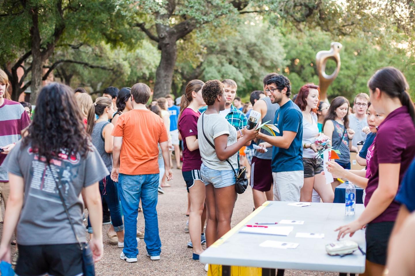 photo of students standing and talking together in a large group outside