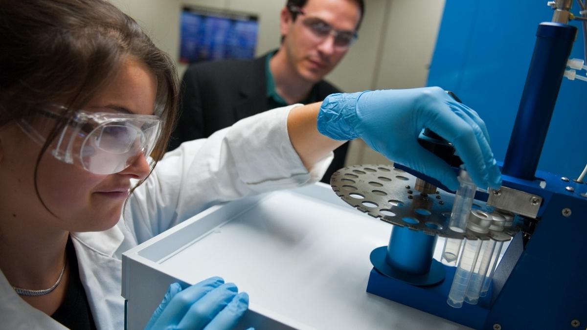 Student working with a test tube as professor observes