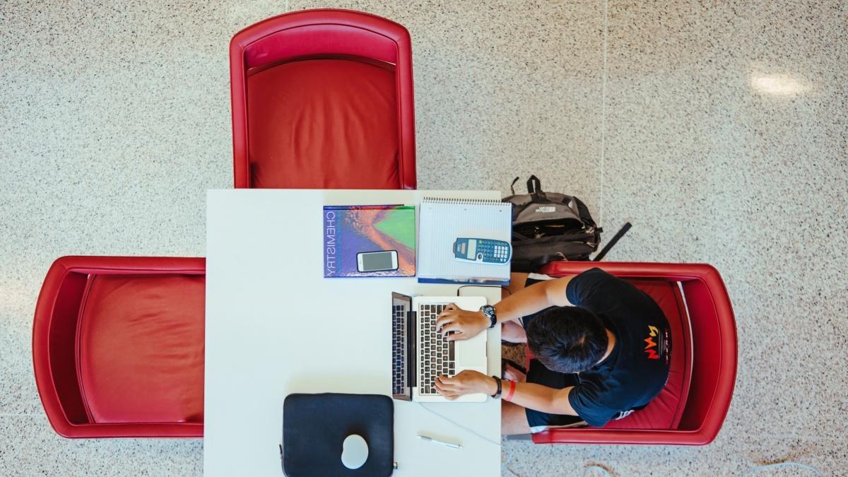 Overhead view of student at table working on computer