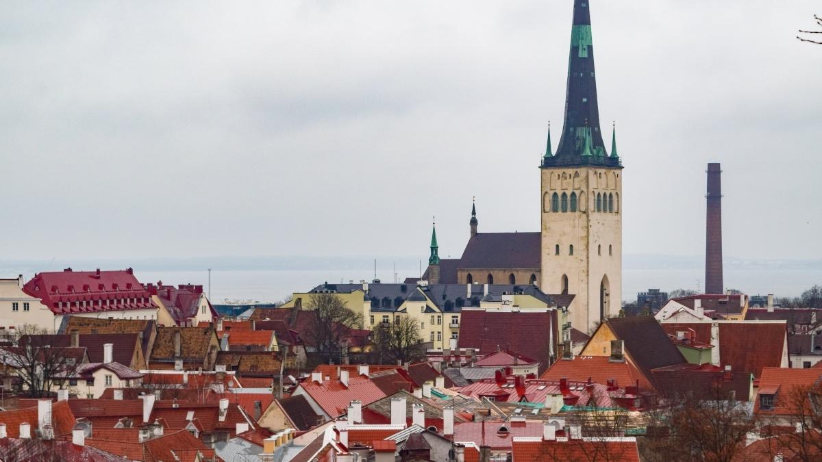 The spire of St. Olav's Church in Tallinn, Estonia towers over the town buildings 