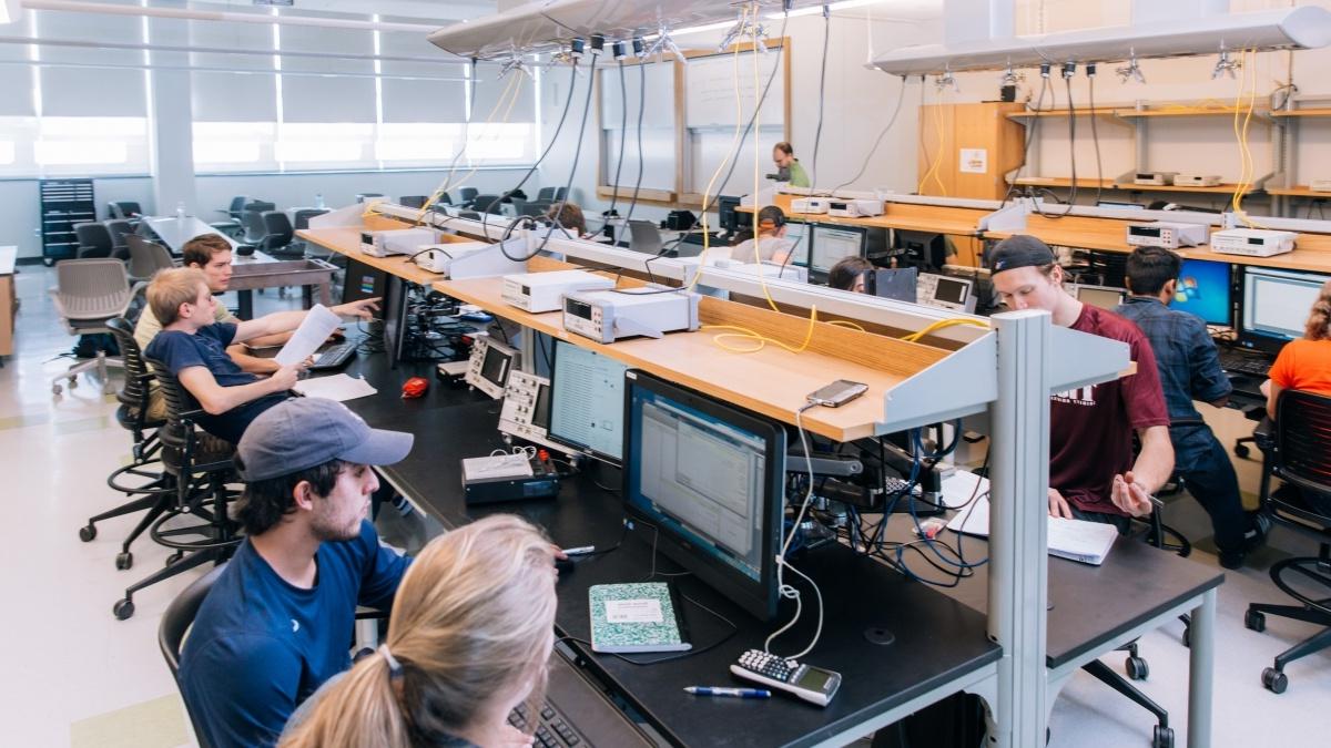 Students in a room, looking at computer screens. 