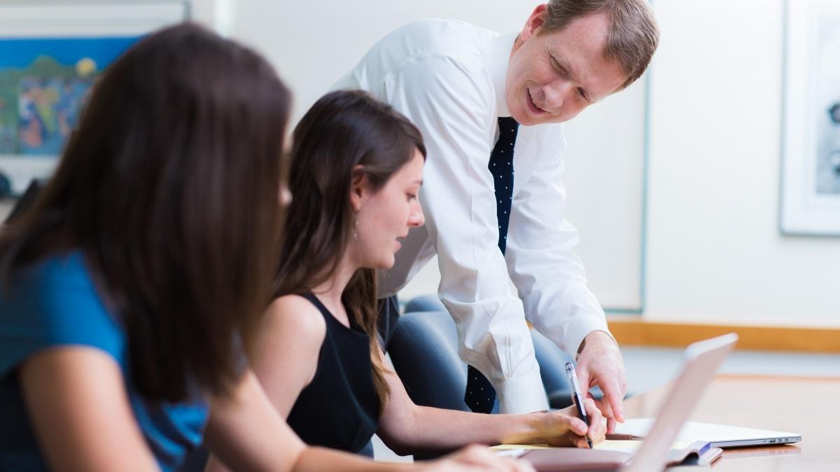 Professor in classroom with two students  