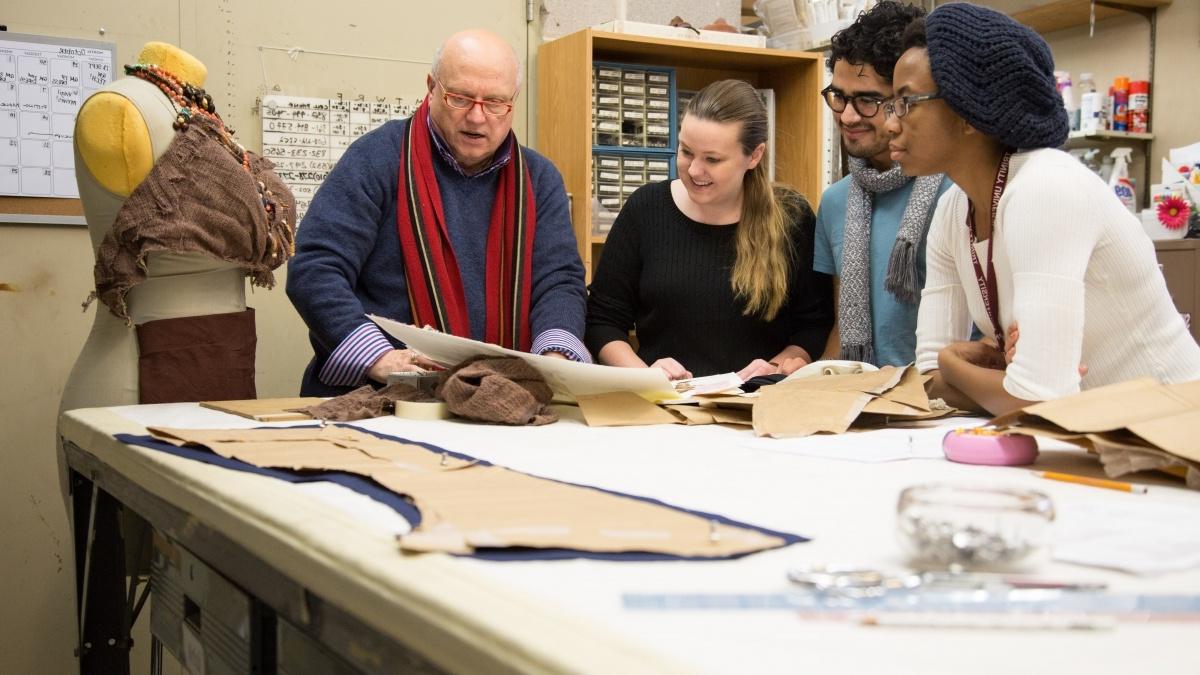 Professor and students working over a costume 