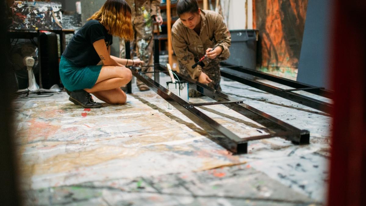 Two students in the paint studio painting for production