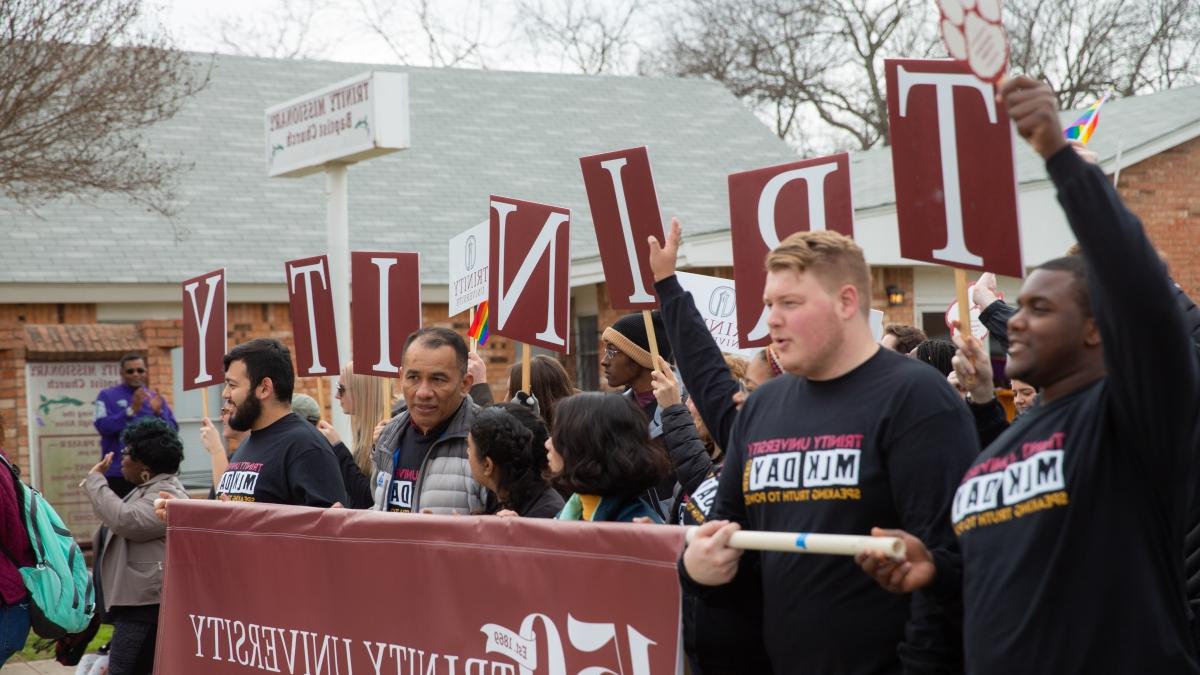 Group of people holding up a 澳门金沙线上赌博官网 University 150th anniversary flag at MLK march 